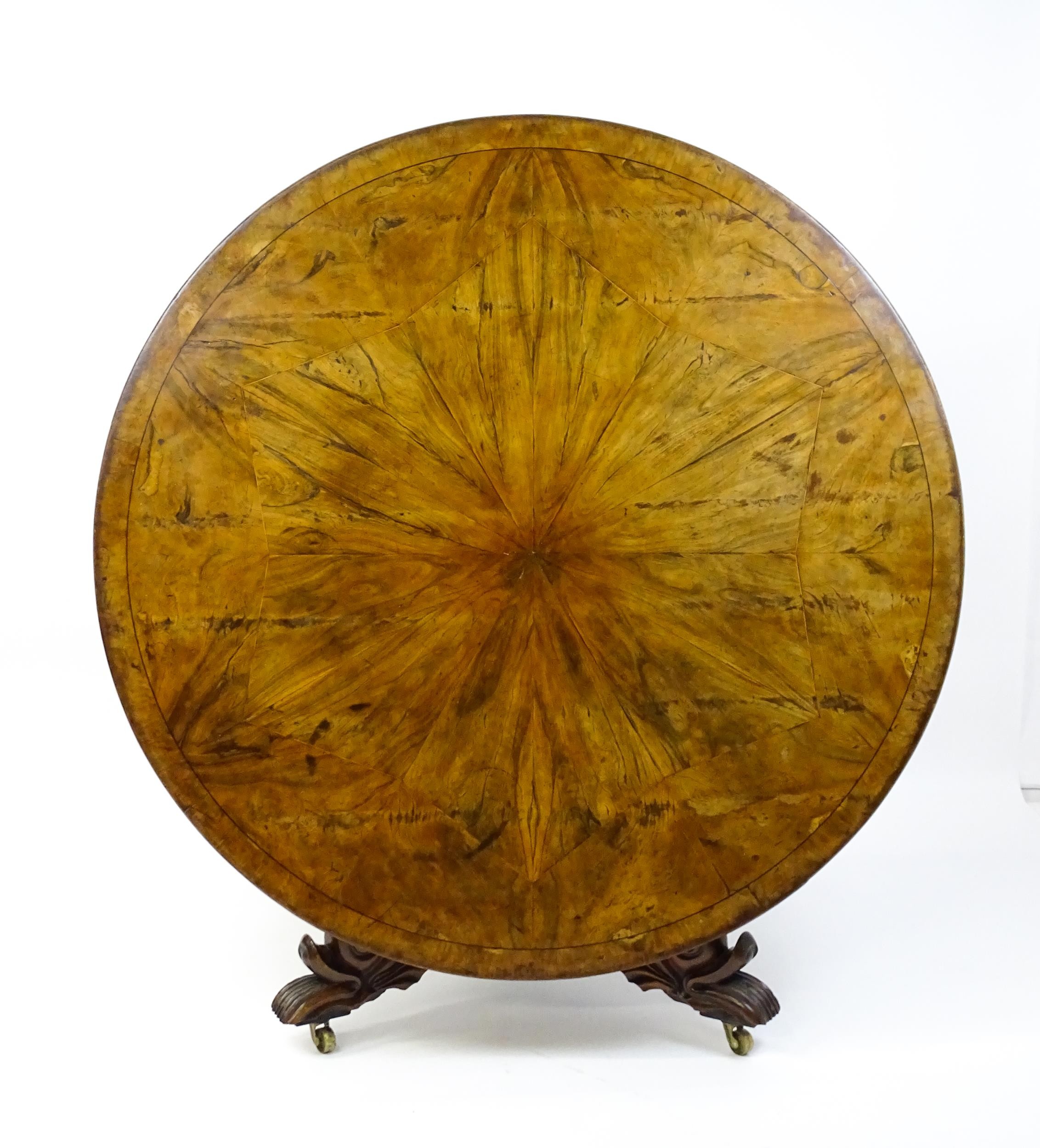 A 19thC dining table with an olive wood veneered circular top raised on a rosewood pedestal with