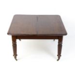 A 19thC mahogany dining table raised on four turned tapering reeded legs terminating in brass