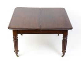 A 19thC mahogany dining table raised on four turned tapering reeded legs terminating in brass
