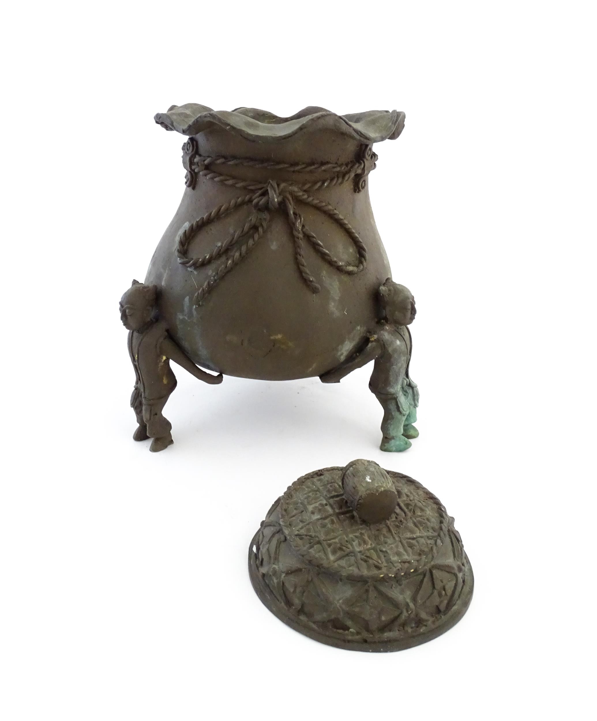 A Chinese cast bronze pot and cover modelled as a money bag with rope tie supported by three figural - Image 9 of 10