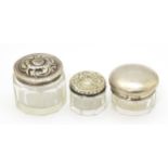 Three assorted panel cut glass dressing table pots with silver lids, hallmarks to include Birmingham