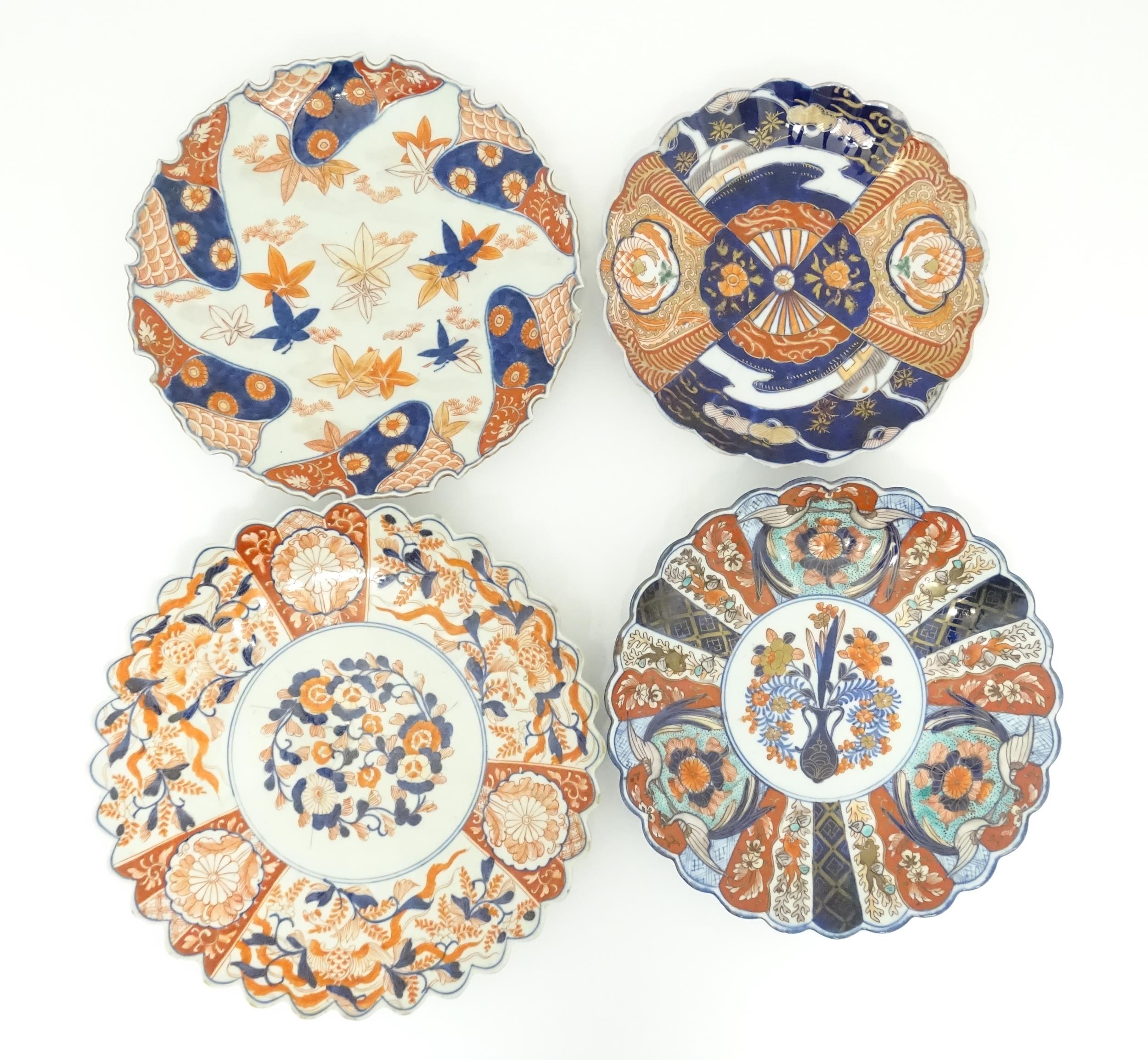 Four Japanese chargers with shaped edges decorated in the Imari palette with flowers, foliage and