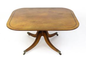 A late Georgian mahogany tilt top dining table with a ebonised stringing, a turned pedestal and