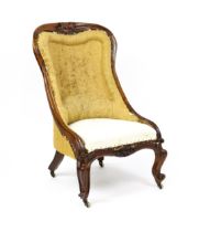 A 19thC rosewood nursing chair with a moulded frame and carved cresting rail raised on carved