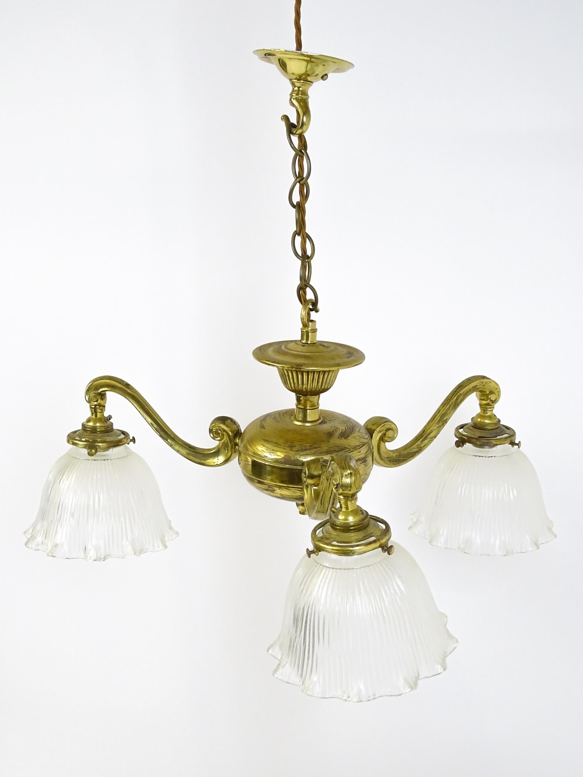 A pair of brass pendant lights having three scrolling branches with three holophane shades. - Image 3 of 16
