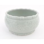 A Chinese celadon planter decorated in relief with peaches and bat detail, and stylised bamboo rims.
