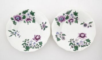 A pair of Lowestoft style saucers decorated with purple and green flowers. Numbered to rim of