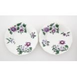 A pair of Lowestoft style saucers decorated with purple and green flowers. Numbered to rim of