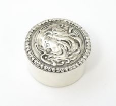 A silver pill box with embossed Art Nouveau style decoration to the hinged lid. Hallmarked London