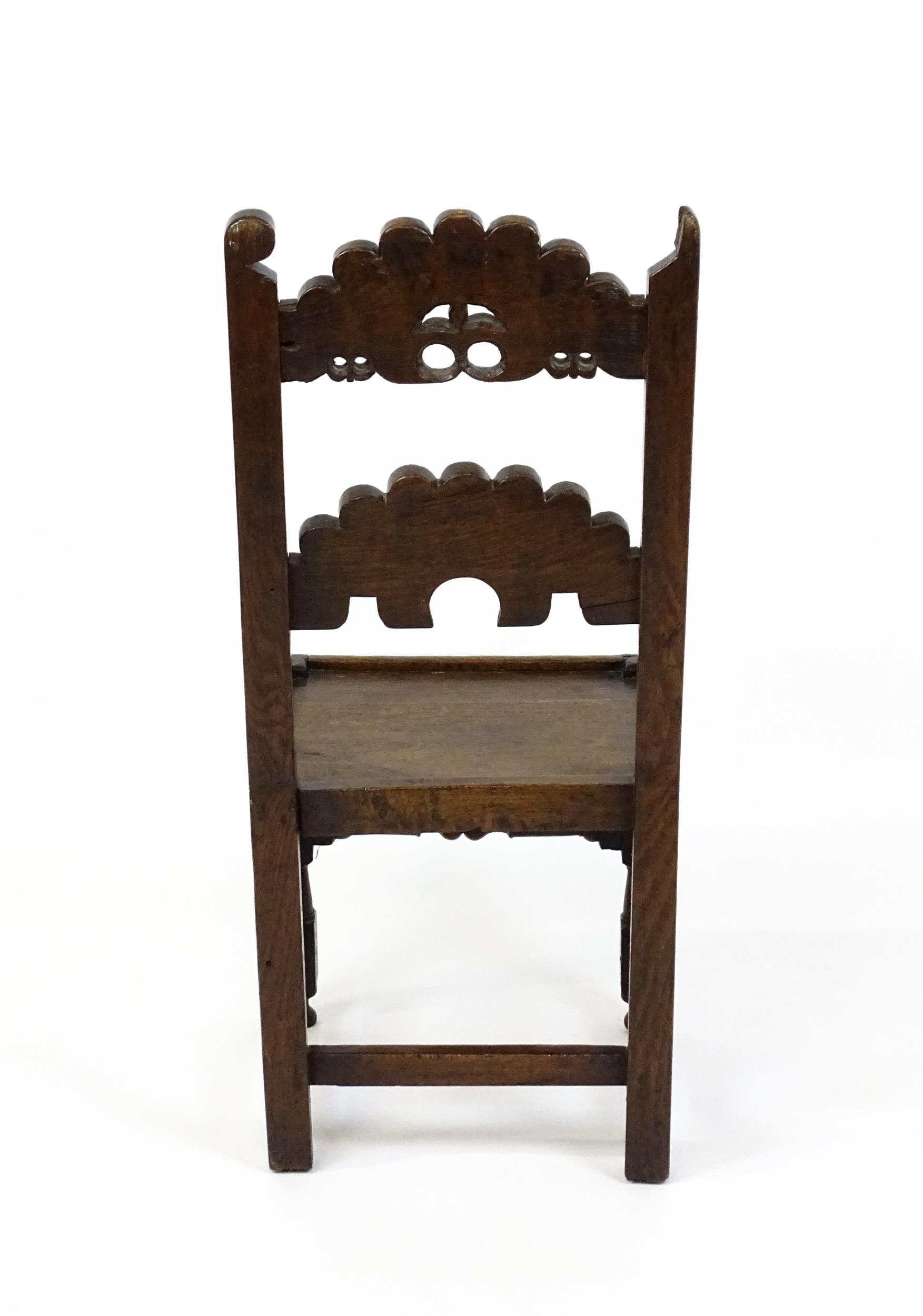 A 17thC oak peg jointed hall chair / back stool with a carved and scrolled top and mid rail raised - Image 2 of 7