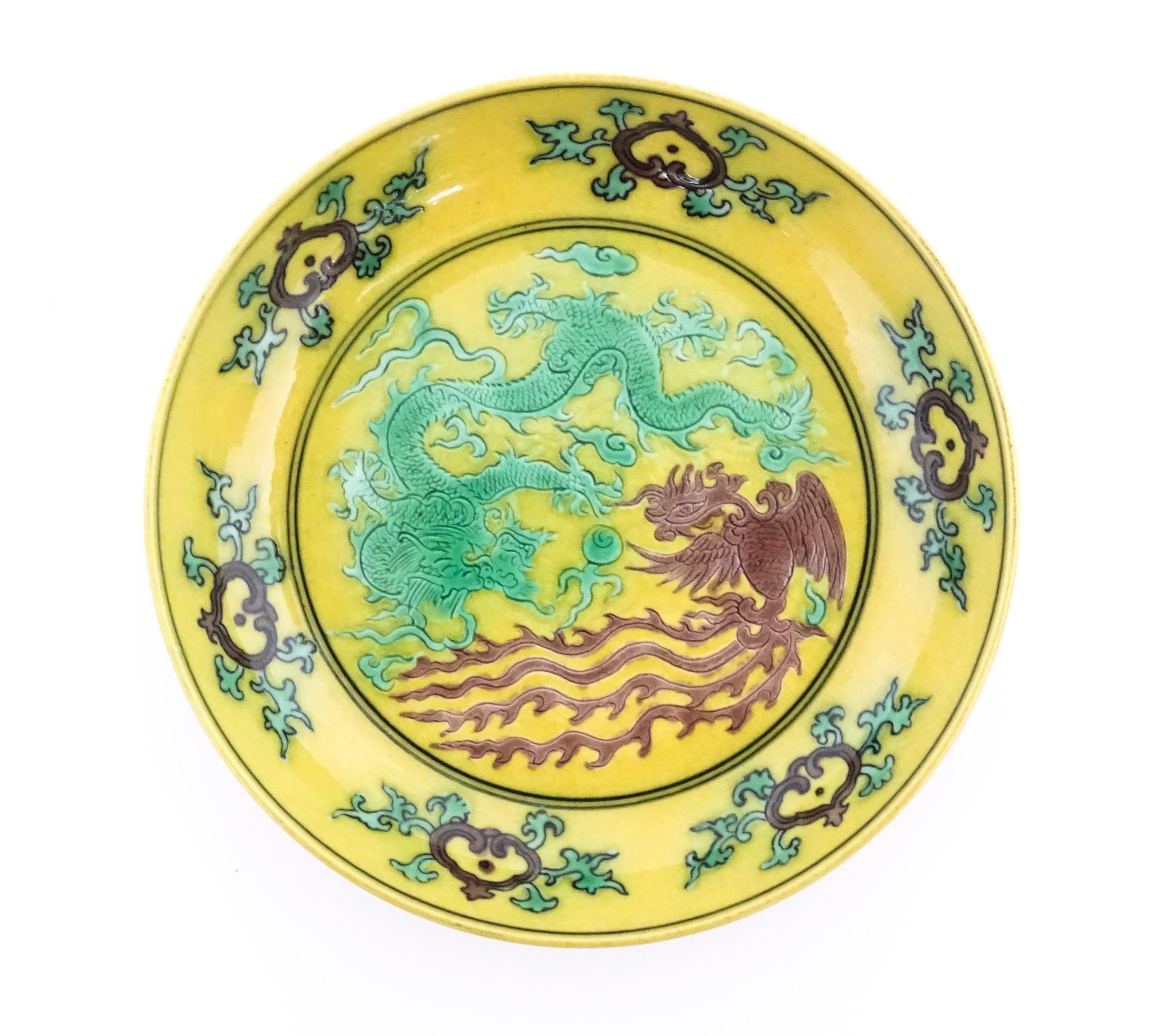 A small Chinese dish with a yellow ground decorated with a dragon, phoenix and flaming pearl.