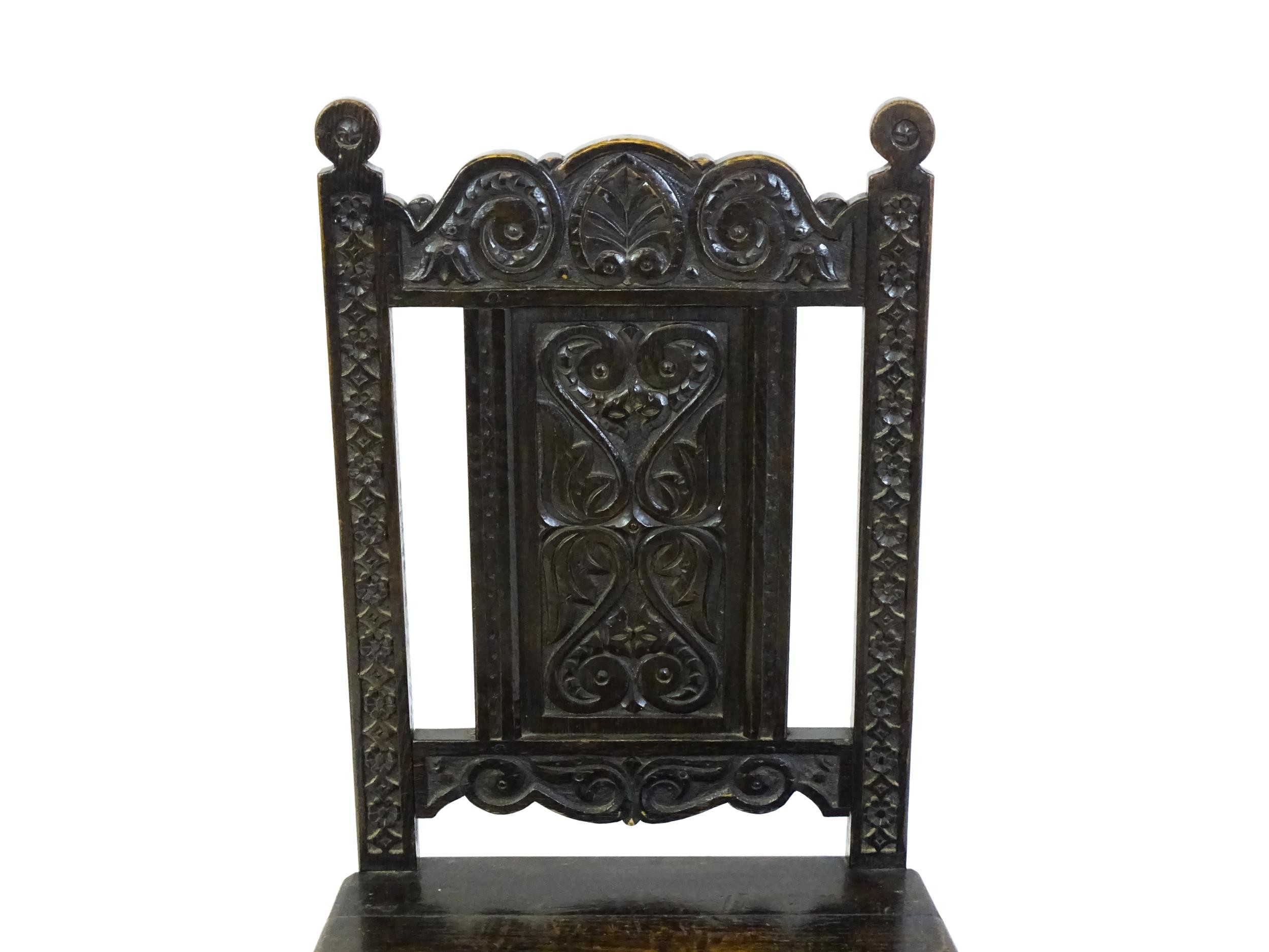 A 19thC carved oak side chair with floral carving, a planked seat and raised on block and turned - Image 3 of 6
