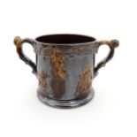 A large Staffordshire treacle glazed frog loving cup decorated in relief with depictions of