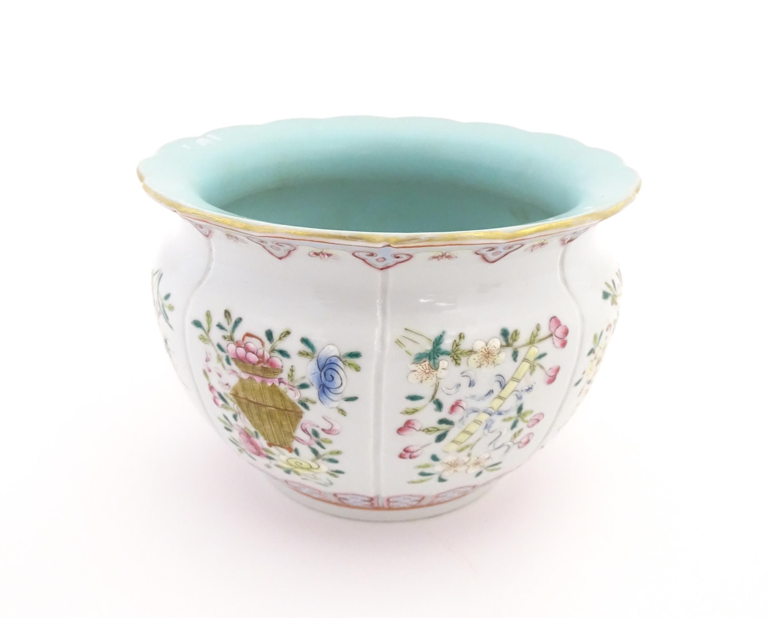 A Chinese famille rose bowl with scalloped edge decorated with flowers, foliage and scrolls.