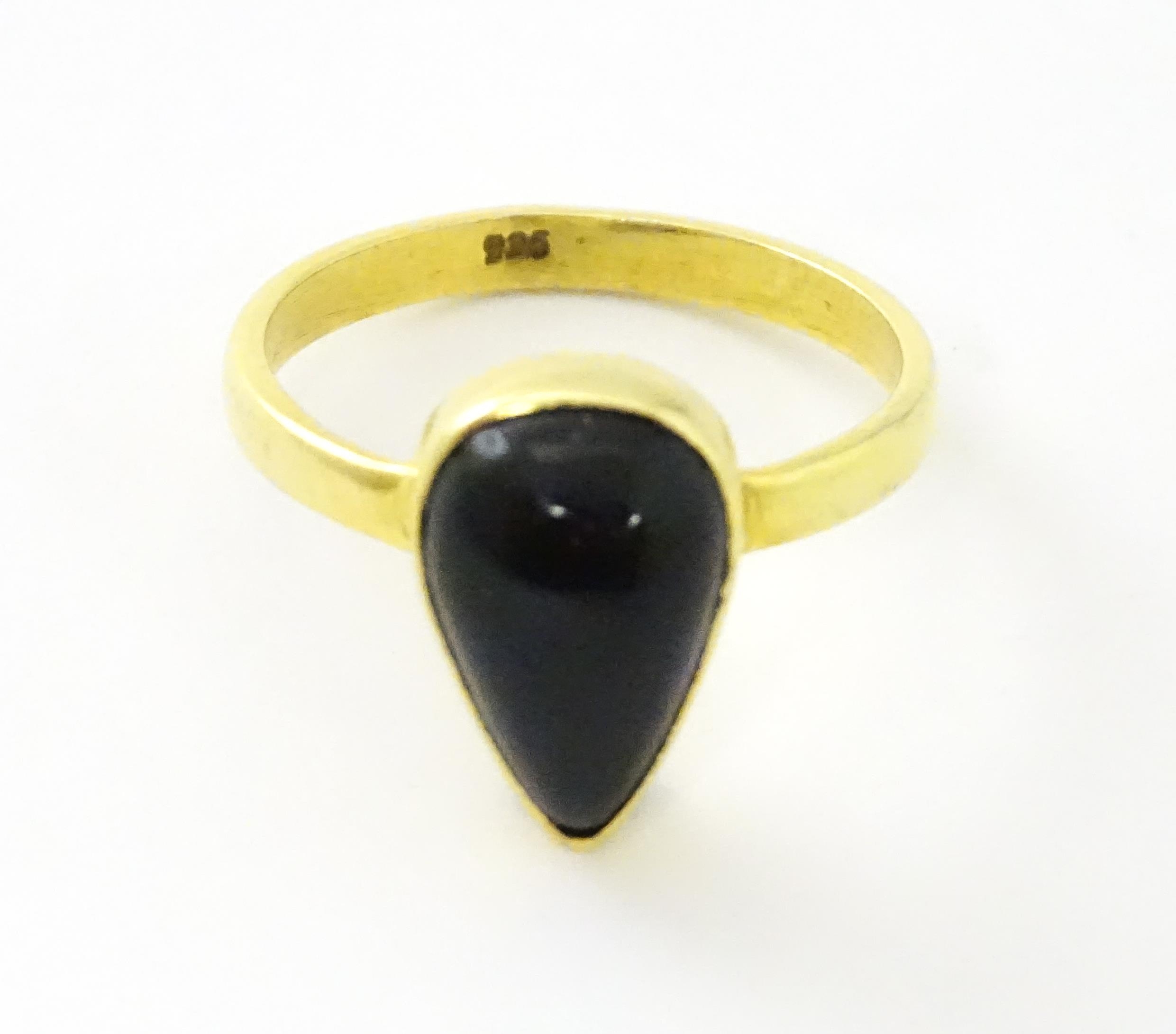 A silver gilt ring set with black opal style cabochon. Ring size approx. O. Please Note - we do