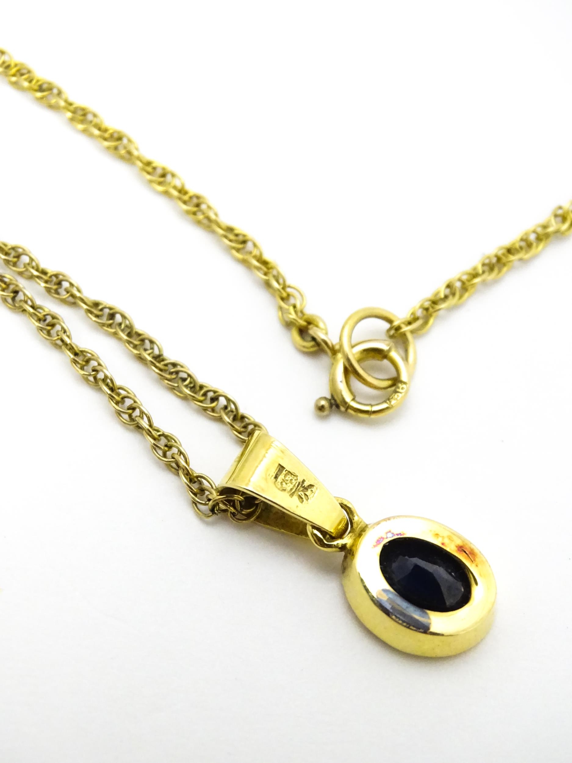 A yellow metal pendant set with central sapphire on a 9ct gold chain. Pendant approx. 1 3/4" long - Image 6 of 6