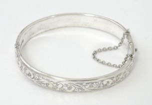 A silver bracelet of bangle form with engraved acanthus scroll decoration. Hallmarked Birmingham