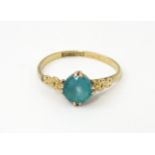 A 9ct gold ring set with aqua coloured glass to centre with engraved detail to shoulders. Ring