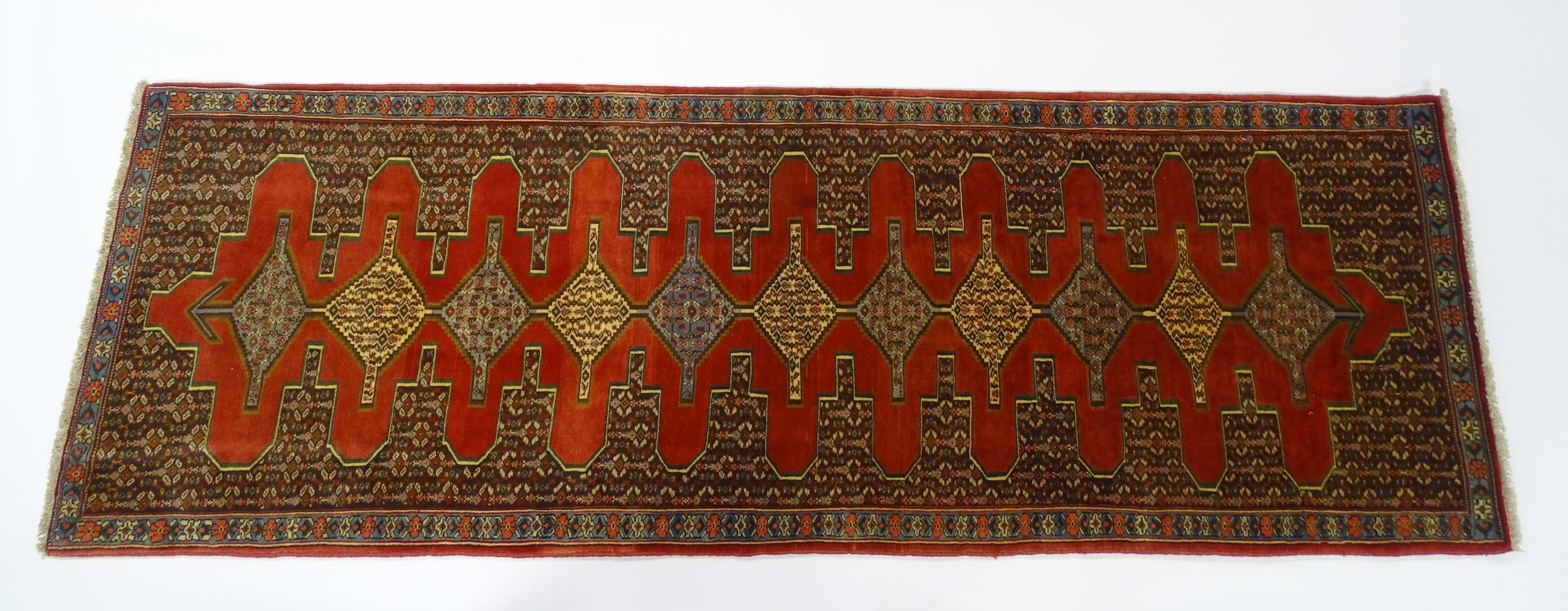 Carpet / Rug : A North West Persian Senneh runner with a red ground decorated with central repeating