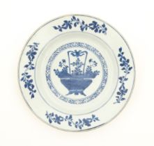 A Chinese blue and white plate depicting a basket of flowers with a foliate border. With blue