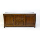 An 18thC oak dresser with a two plank top above two panelled cupboards and three central drawers