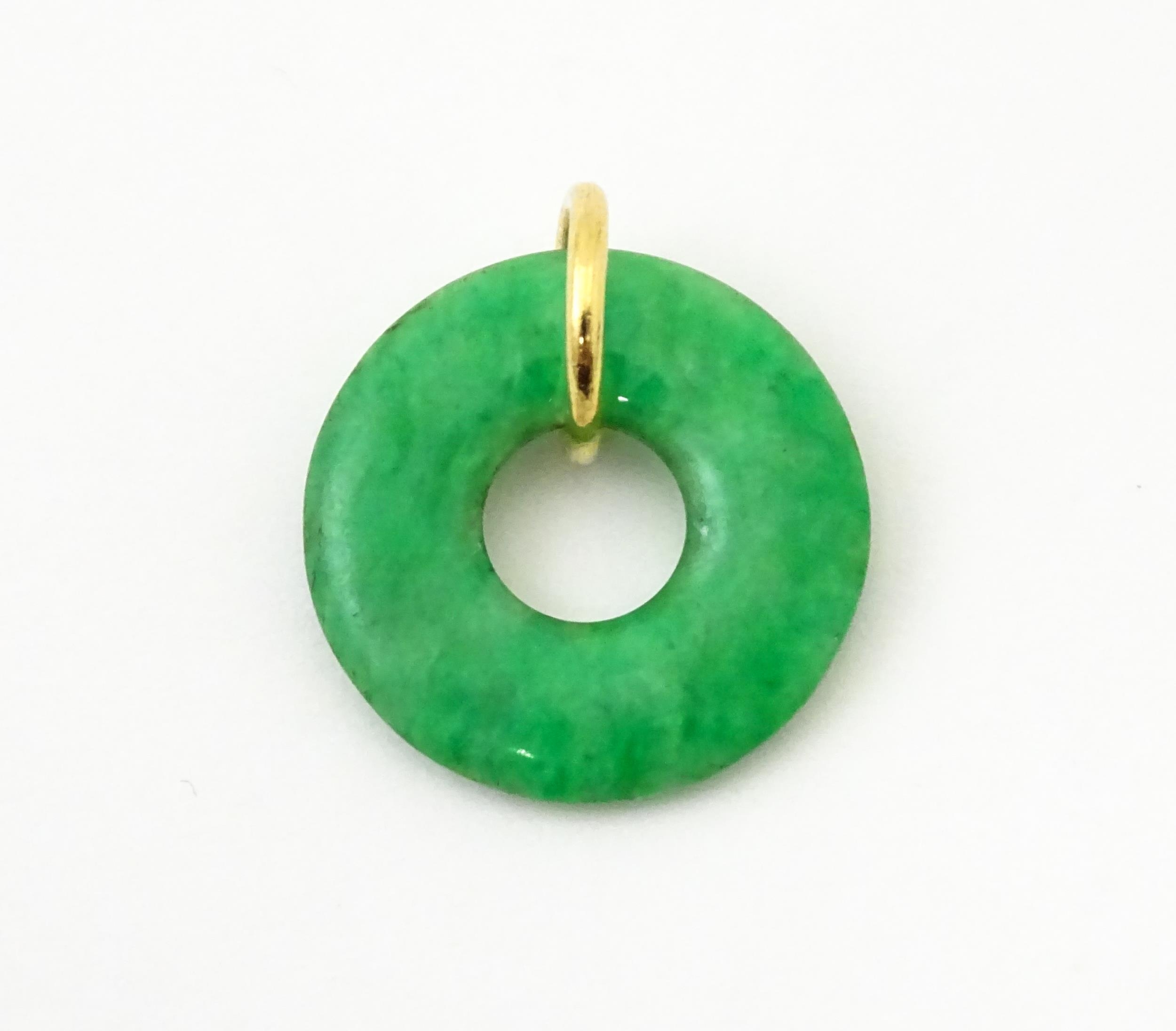 A green jade coloured hardstone pendant with yellow metal mount. Approx 3/4" wide Please Note - we