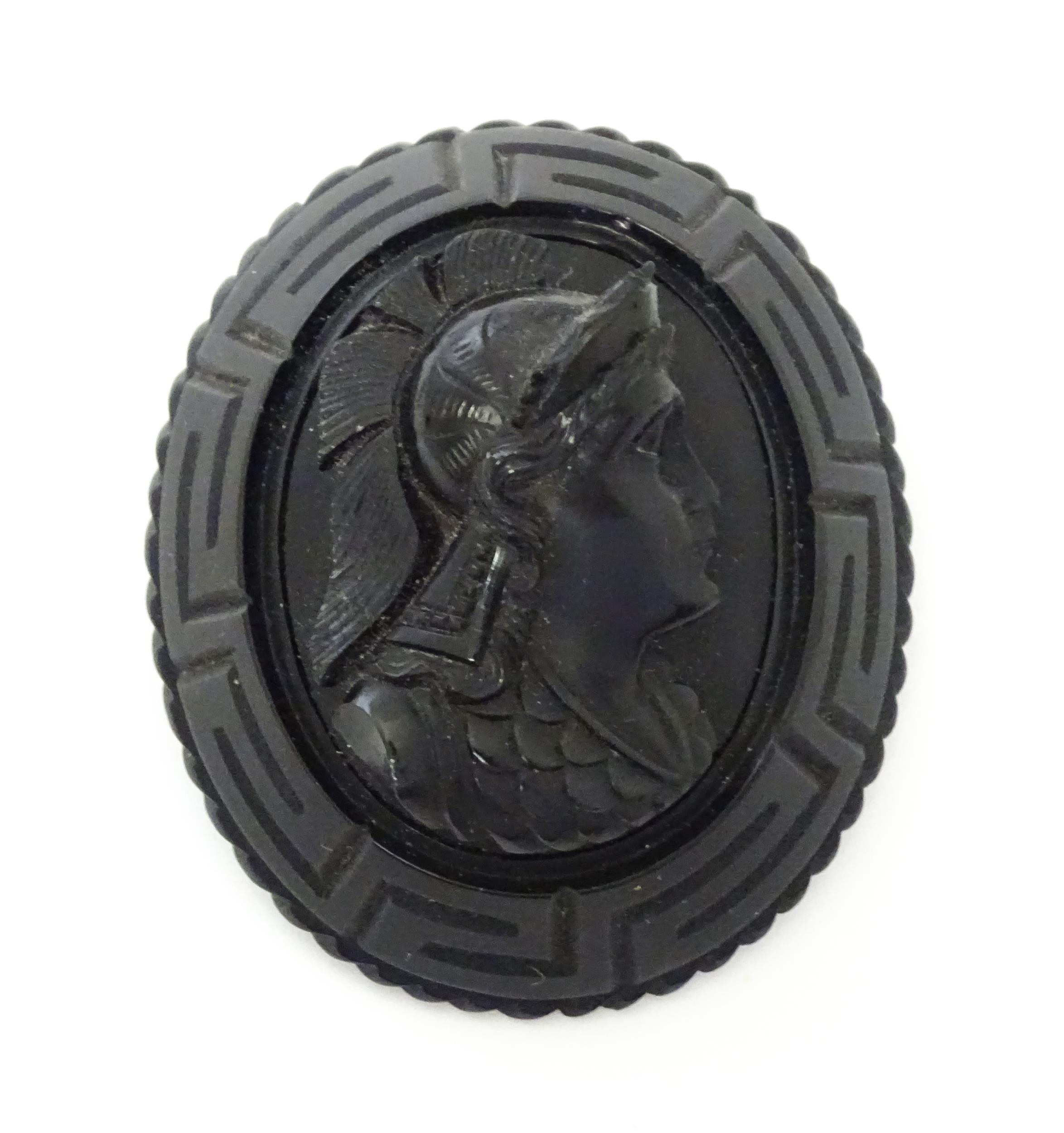 A Victorian Whitby jet cameo brooch depicting the head of a Roman solider, within a Greek key mount.