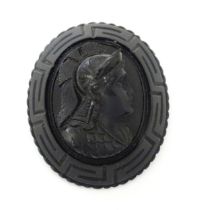 A Victorian Whitby jet cameo brooch depicting the head of a Roman solider, within a Greek key mount.