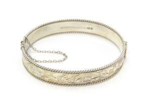 A silver bracelet of bangle form with engraved foliate decoration. Approx. 2 1/2" wide Please Note -