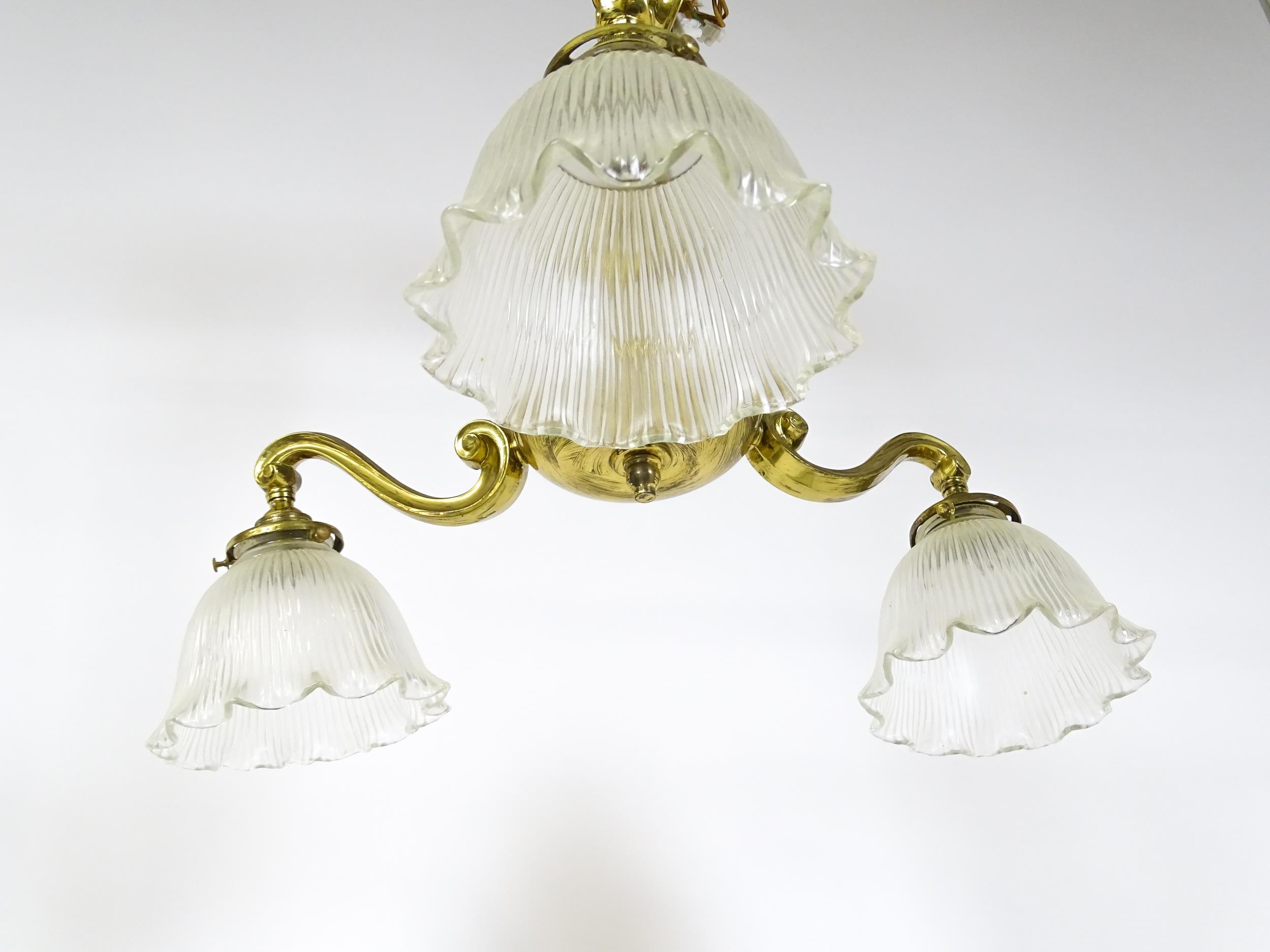 A pair of brass pendant lights having three scrolling branches with three holophane shades. - Image 11 of 16