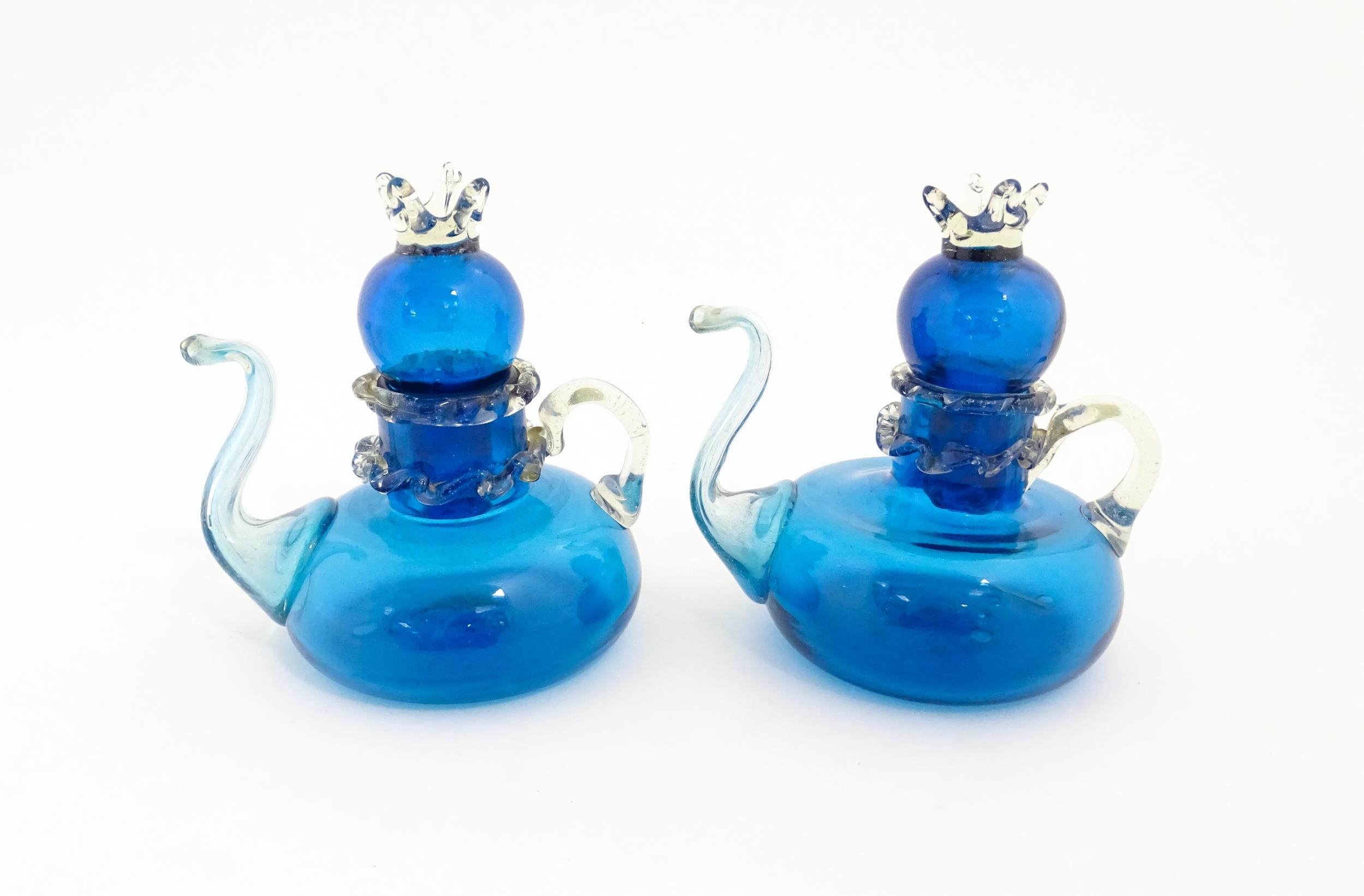 An unusual pair of turquoise glass oil / vinegar bottles of teapot form, the lids surmounted by