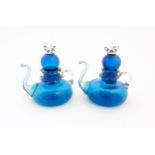 An unusual pair of turquoise glass oil / vinegar bottles of teapot form, the lids surmounted by