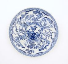 A Chinese blue and white plate decorated with central taihu rock and flowers, bordered by figures in