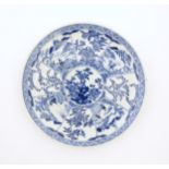 A Chinese blue and white plate decorated with central taihu rock and flowers, bordered by figures in