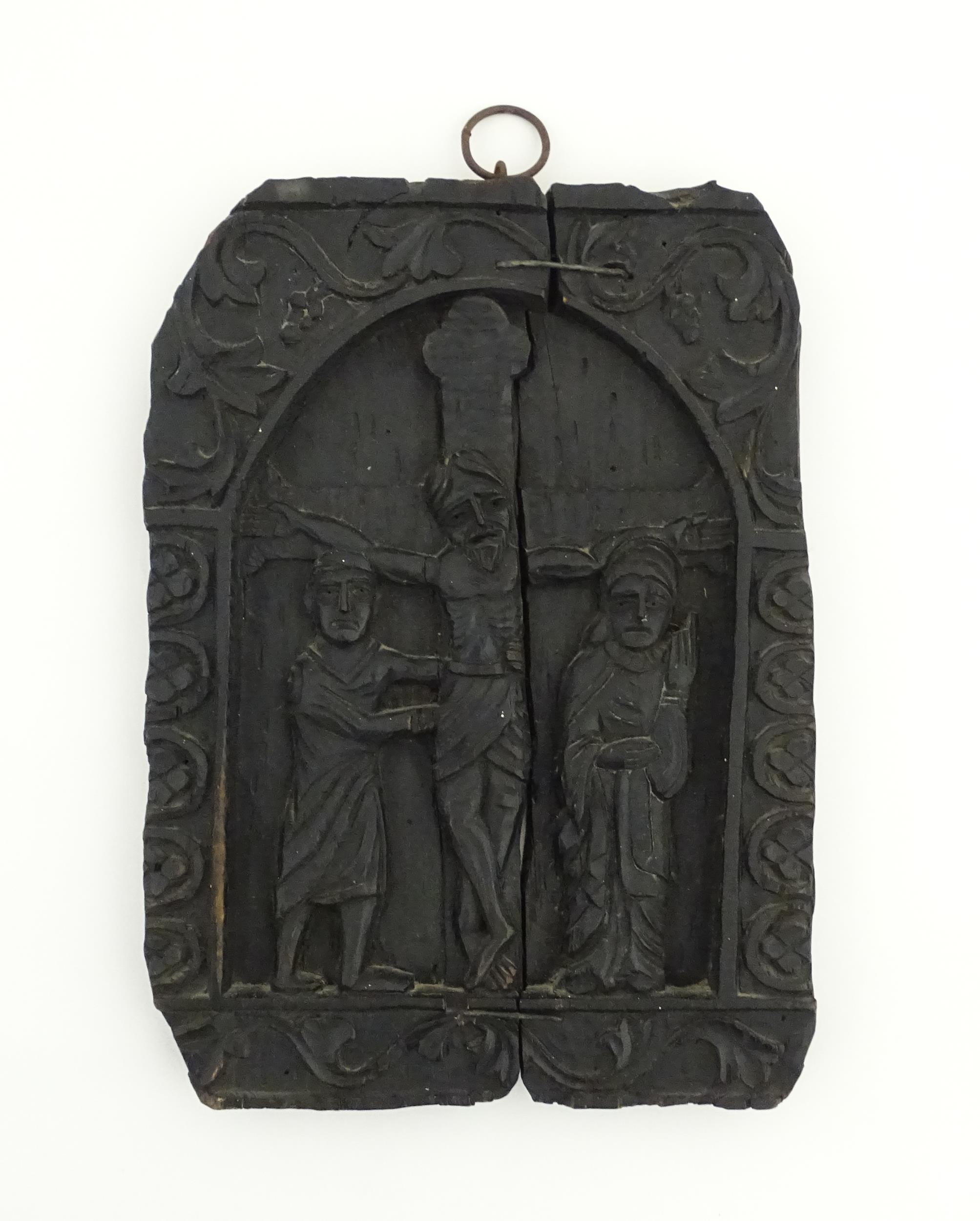 A naive carved wooden plaque depicting the crucifixion of Christ with the Virgin Mary and St.