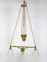 An early 20thC rise and fall adjustable height pendant light with with brass detail and twin frosted