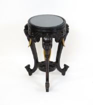 An early 20thC ebonised occasional table with three elephant formed supports united by a pierced