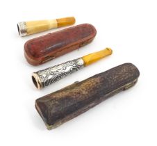 Two amber cheroot mouthpiece holders with white metal mounts, one with meerschaum detail. On