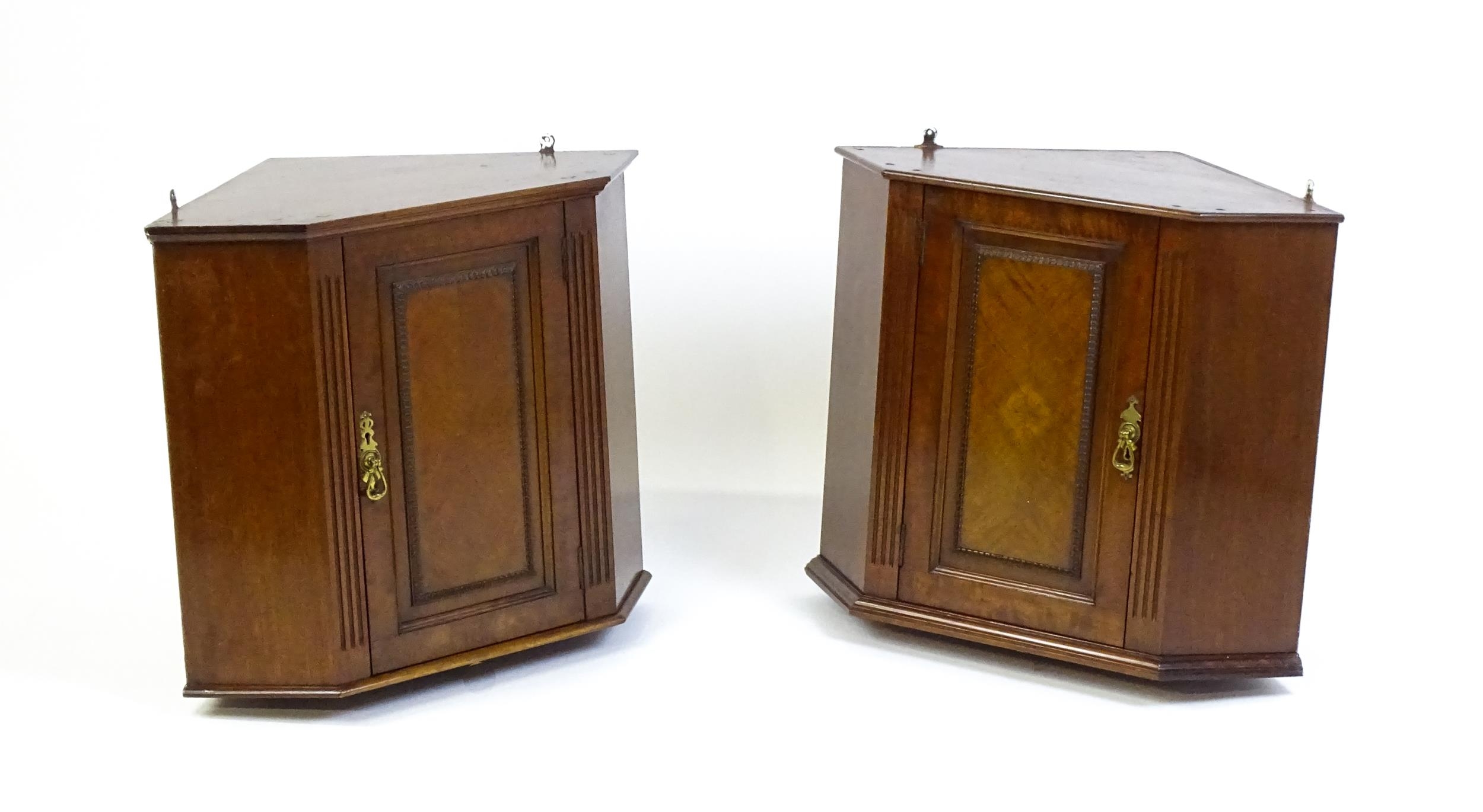 A pair of mid 20thC walnut corner cabinets. Bearing labels to back panels. 21 1/2 high x 26" wide