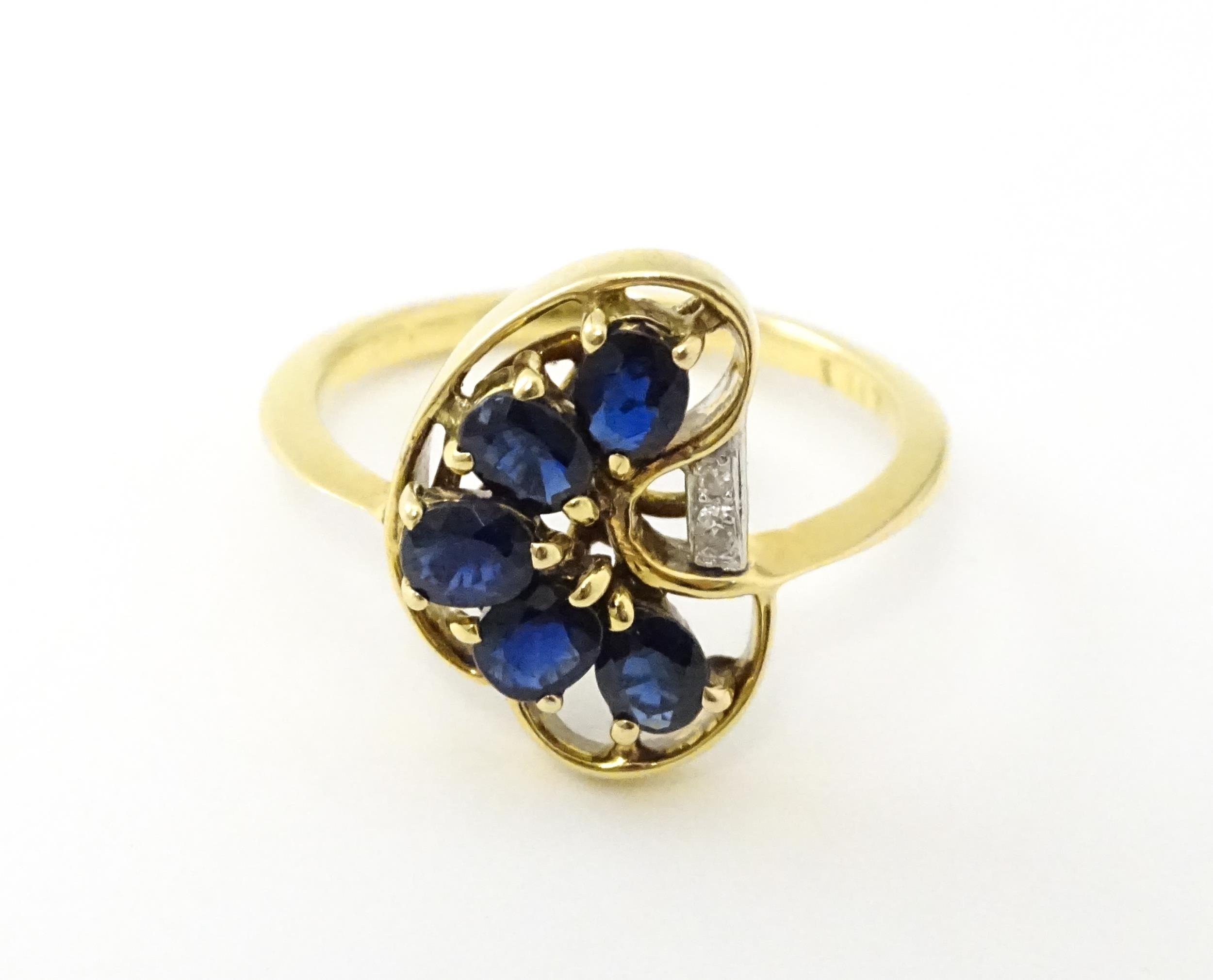 A 9ct gold ring set with 5 graduated blue spinel and two diamonds. Ring size approx. L 1/2 Please