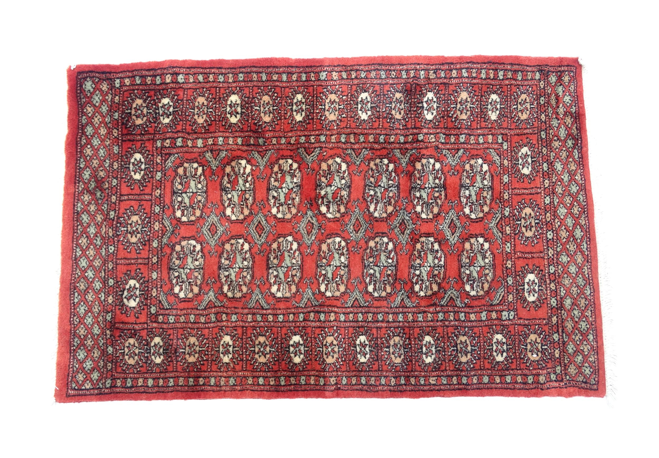 Carpet / Rug : A Pakistan wool red ground rug decorated with repeating geometric motifs with further