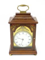 A 20thC walnut cased mantle clock with inlaid floral detail and white enamel dial with Roman chapter