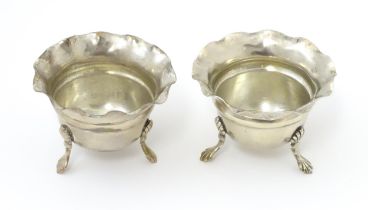 A pair of silver salts with crimped rims and raised on 3 paw feet. Hallmarked Birmingham 1931