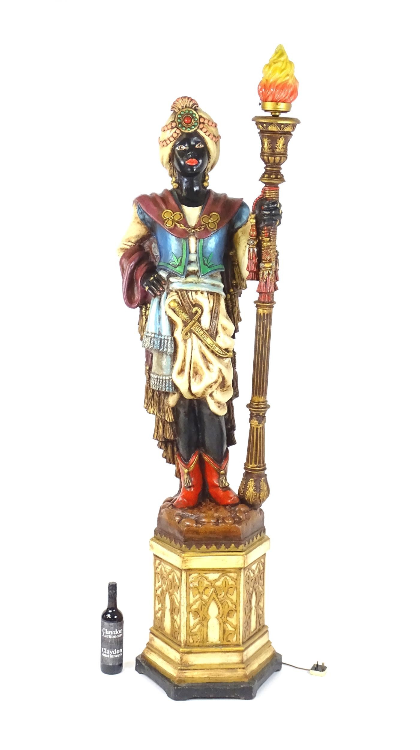 A mid 20thC blackamoor lamp, the lamp having a polychrome figural top grasping a torchiere, the