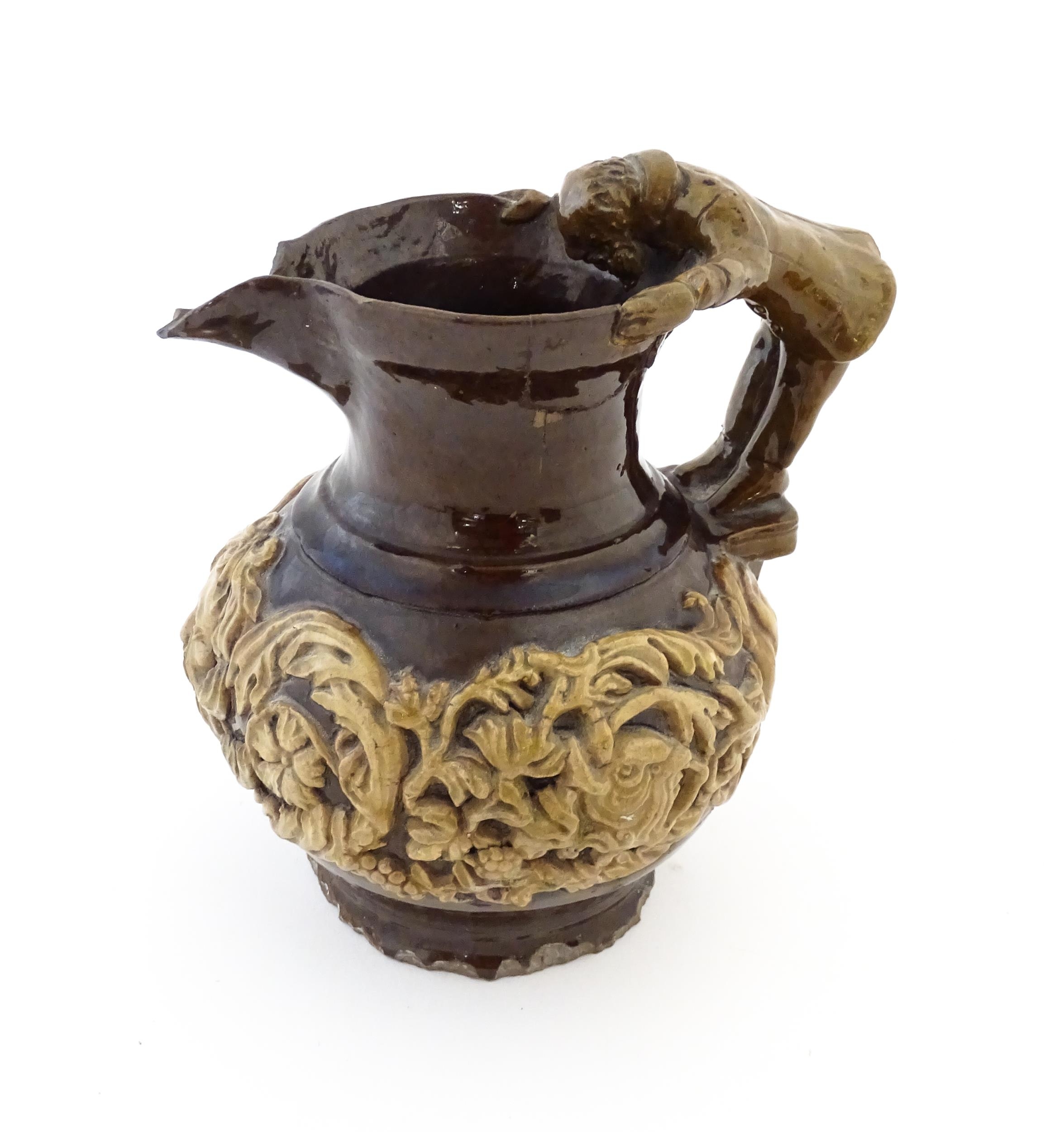 A 19th century Castle Hedingham treacle glazed jug by Edward Bingham with banded relief foliate