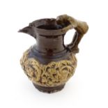 A 19th century Castle Hedingham treacle glazed jug by Edward Bingham with banded relief foliate