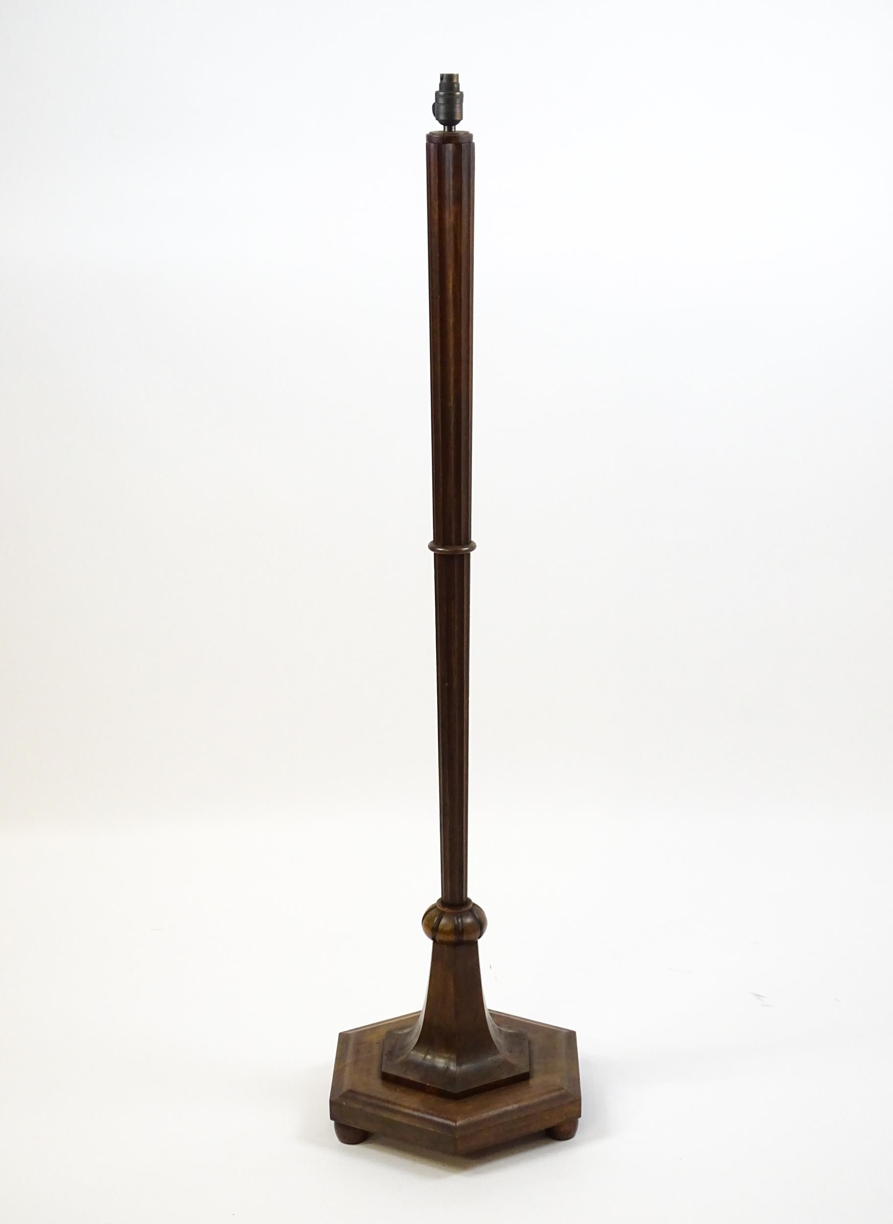 An Art Deco style oak standard lamp with a chamfered stem and a moulded hexagonal base. Approx.