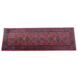 Carpet / Rug : A red ground runner with repeating motifs to centre, bordered by geometric banding.