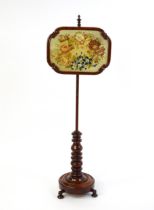 A mid 19thC mahogany pole screen, with a glazed adjustable screen having a needlework centre and