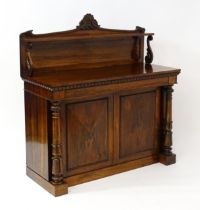 A 19thC rosewood chiffonier with a shaped upstand surmounted by a carved crest and a long shelf